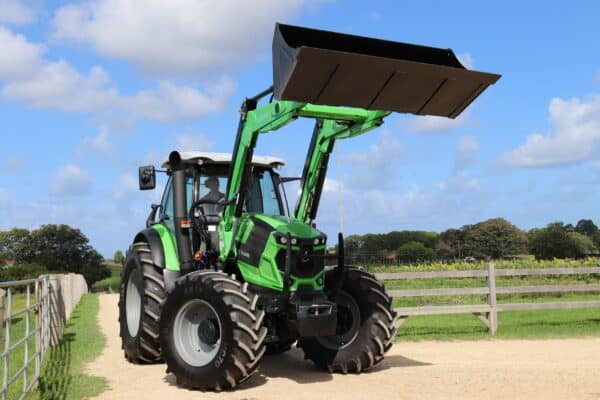 A Green Deutz Tractor with a raised Loader and 4in1 Bucket on a Dirt Road