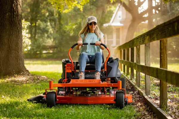 Lady driving an orange ride on mower